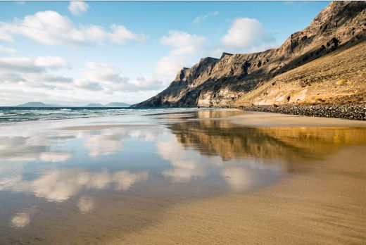 Faszinierendes Famara – Der längste Strand Lanzarotes lockt Surfer und Erholungssuchende Der kilometerlange feine Sandstrand von Famara bietet ausreichend Platz für Erkundungstouren durch weitgehend unberührte Natur. Bildnachweis: Turismo Lanzarote